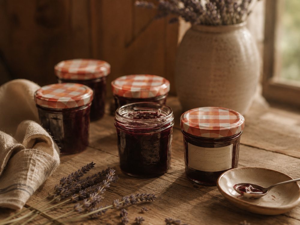 Small jars of lavender jam with gingham lids and a sprig of lavender